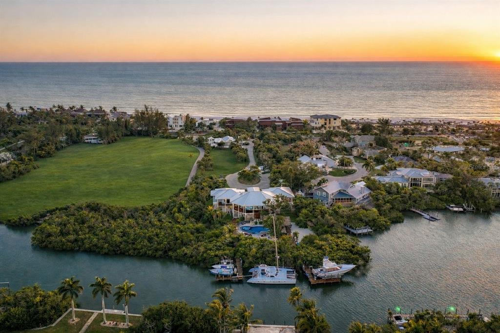An aerial view of a waterfront home with a pool, boat docks, and grassy lawn — 6680 GULF OF MEXICO DRIVE, LONGBOAT KEY, FL