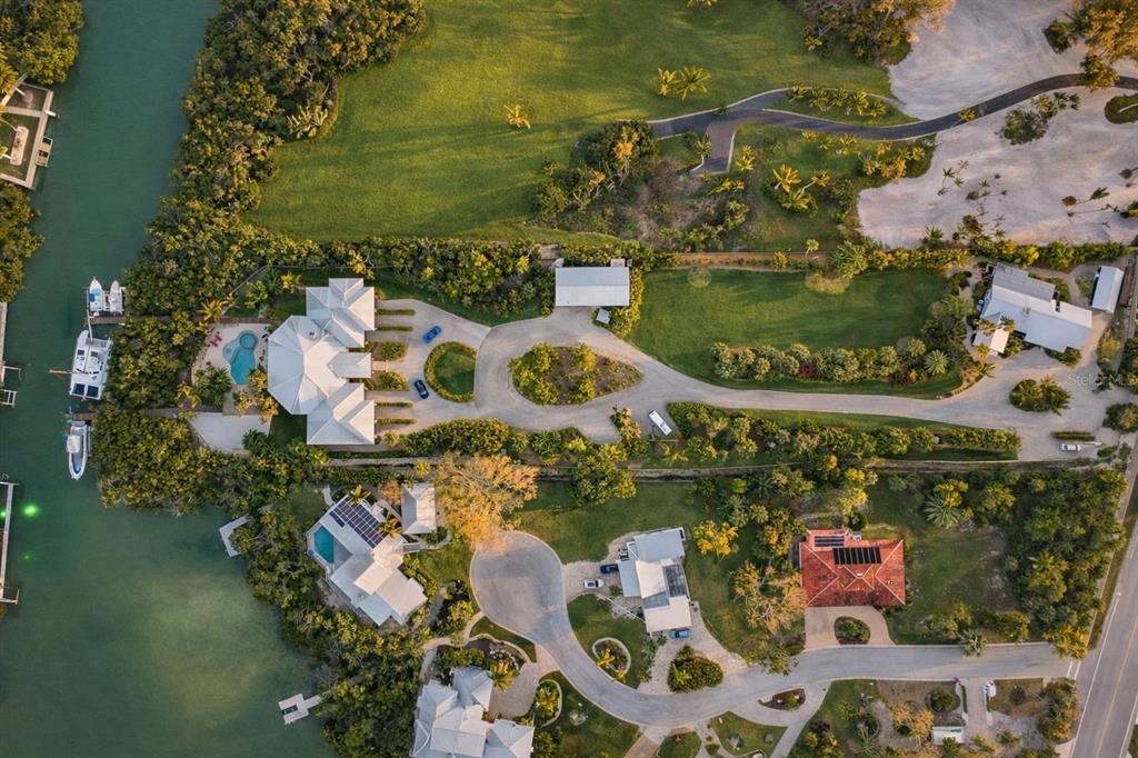 An aerial view shows waterfront homes with pools, docks, and lush landscaping along a canal — 6680 GULF OF MEXICO DRIVE, LONGBOAT KEY, FL