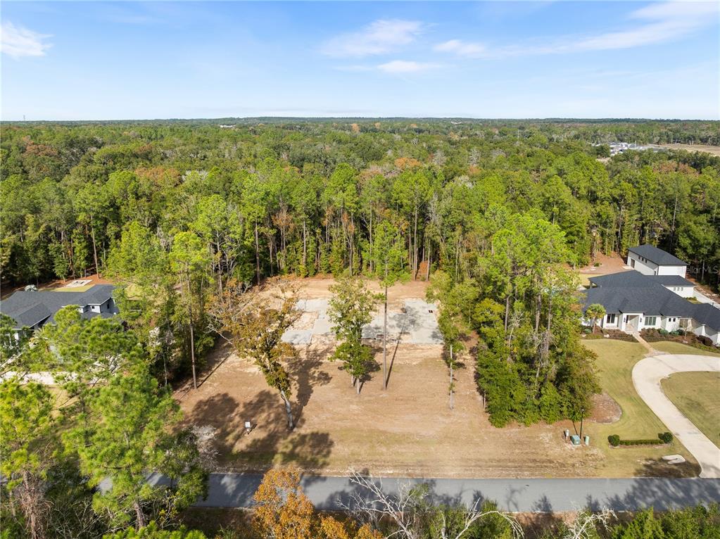 An aerial view shows a cleared residential lot with a concrete foundation surrounded by trees — 12364 SW 16TH LANE, NEWBERRY, FL