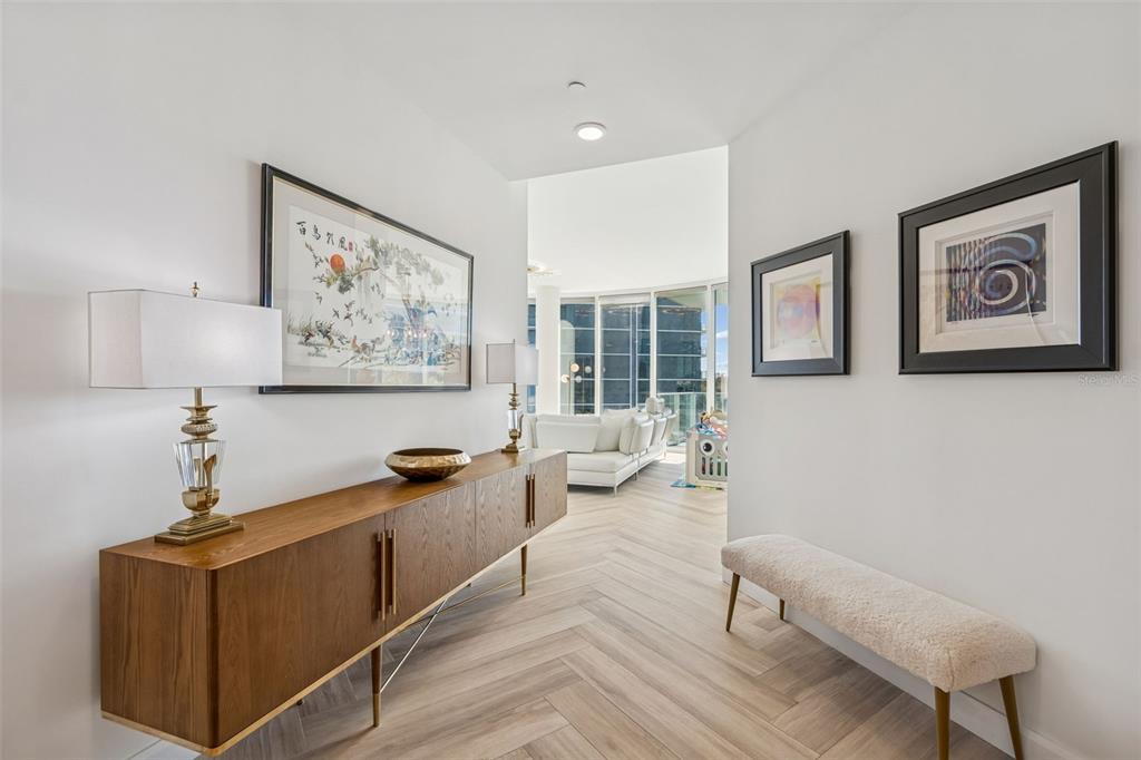 A bright hallway features a wooden console table, a bench, and artwork on white walls — 2900 W BAY TO BAY BOULEVARD UNIT 501, TAMPA, FL