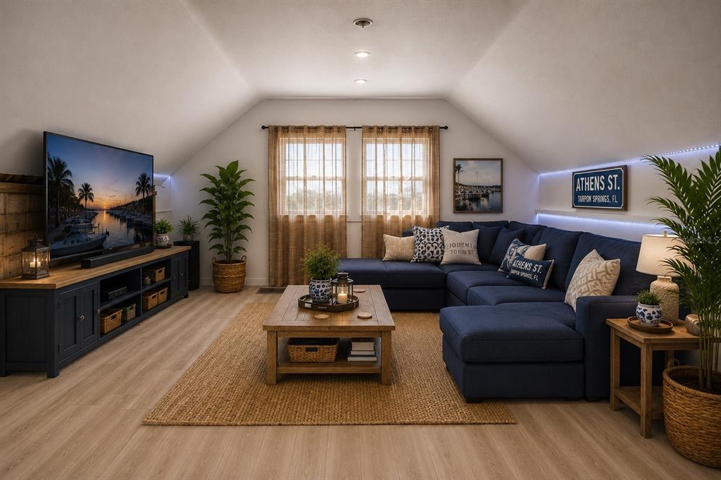 A cozy attic living room features a blue sectional sofa, wood coffee table, and television — 531 ATHENS STREET, TARPON SPRINGS, FL