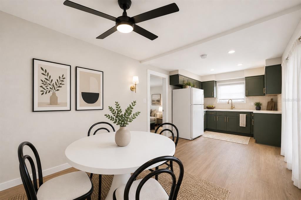 A dining area with a round white table sits adjacent to a kitchen with green cabinets — 531 ATHENS STREET, TARPON SPRINGS, FL