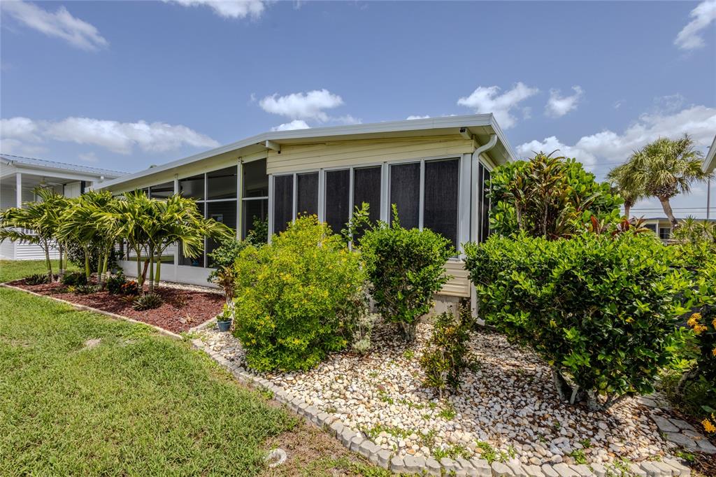 A light-colored mobile home features a screened-in porch and landscaped yard with palm trees — 2100 KINGS HIGHWAY UNIT 274, PORT CHARLOTTE, FL