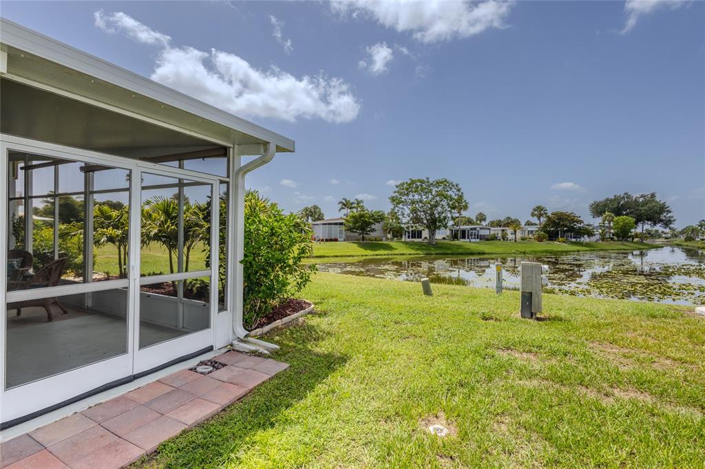 A screened-in patio overlooks a grassy lawn and a small pond with lily pads — 2100 KINGS HIGHWAY UNIT 274, PORT CHARLOTTE, FL