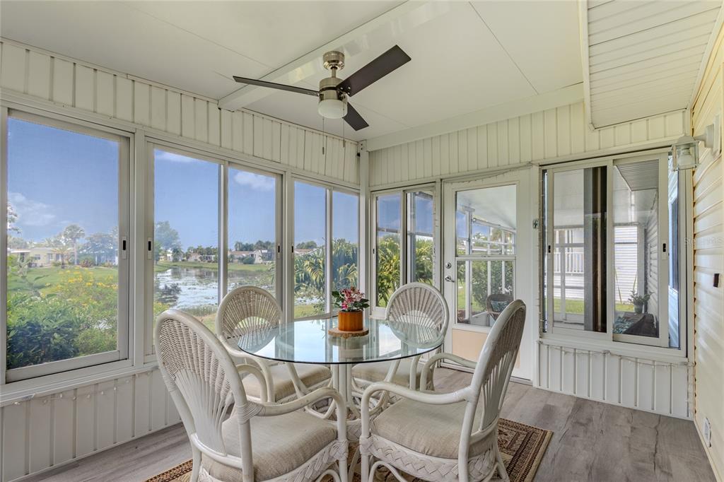 A sunroom with a glass-top dining table, wicker chairs, ceiling fan, and views of water — 2100 KINGS HIGHWAY UNIT 274, PORT CHARLOTTE, FL