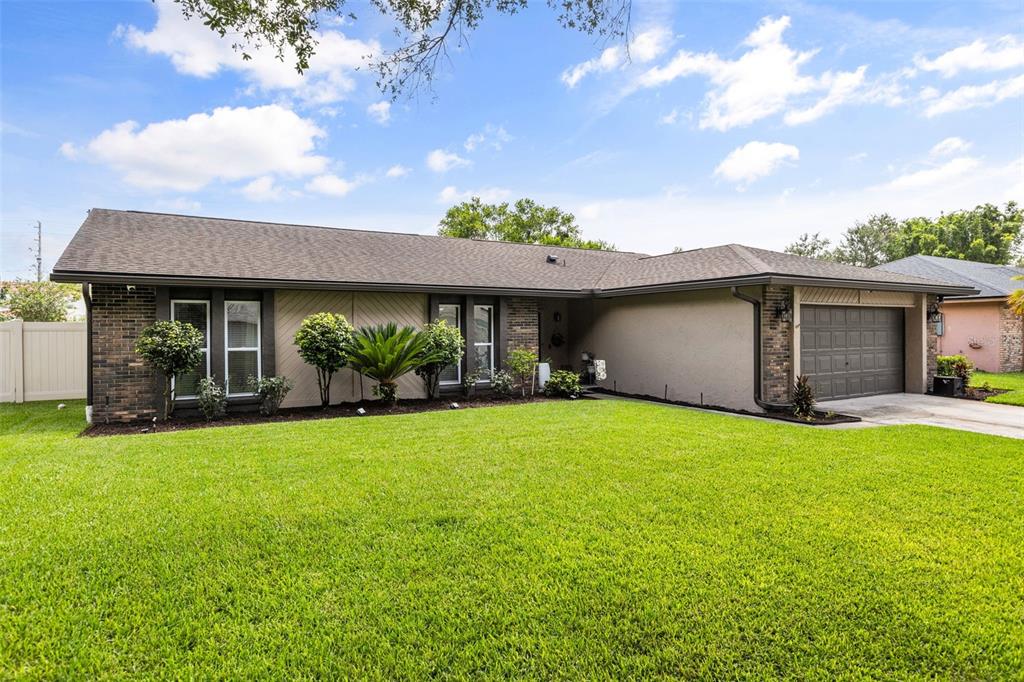 A single-story house with a brick and stucco exterior, a two-car garage, and a lawn — 8736 LARWIN LANE, ORLANDO, FL