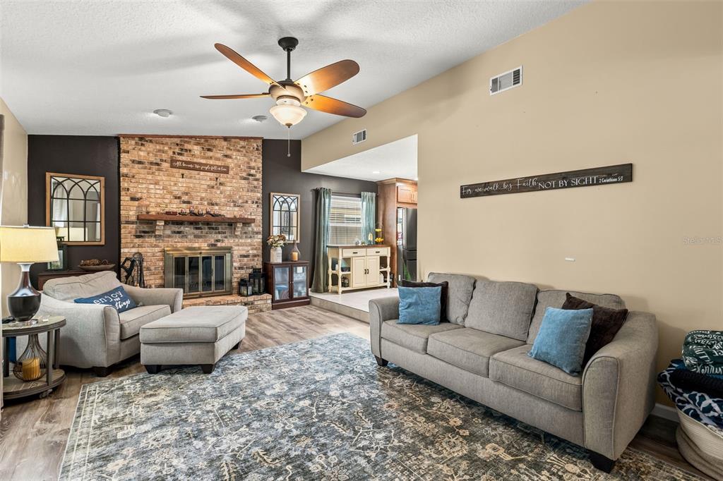A living room features a brick fireplace, a gray sofa, and a patterned area rug — 8736 LARWIN LANE, ORLANDO, FL