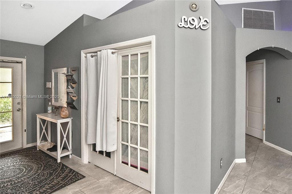 An entryway features gray walls, tile flooring, a white console table, and French doors — 2612 66 st w, Lehigh Acres FL 33971, LEHIGH ACRES, FL