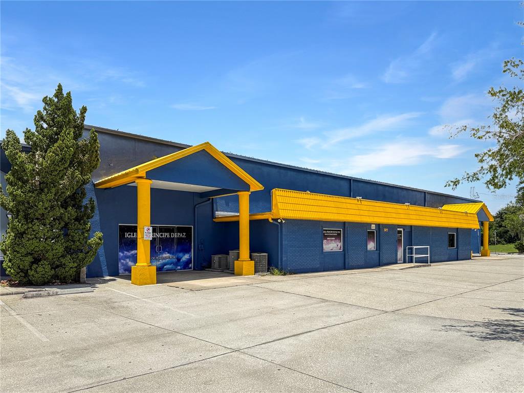 A blue commercial building with a yellow roof and a covered entrance stands outdoors — 307 W BASS STREET, KISSIMMEE, FL