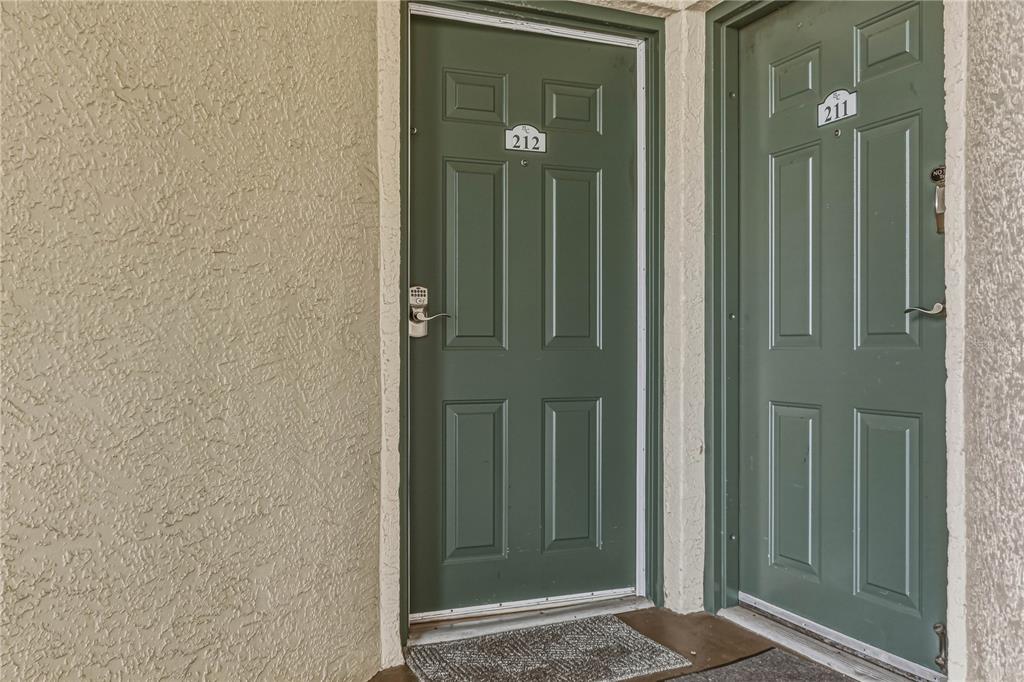 Two green apartment doors labeled 212 and 211 are set in a textured beige wall — 8800 BAY PINES BOULEVARD UNIT 212, ST PETERSBURG, FL
