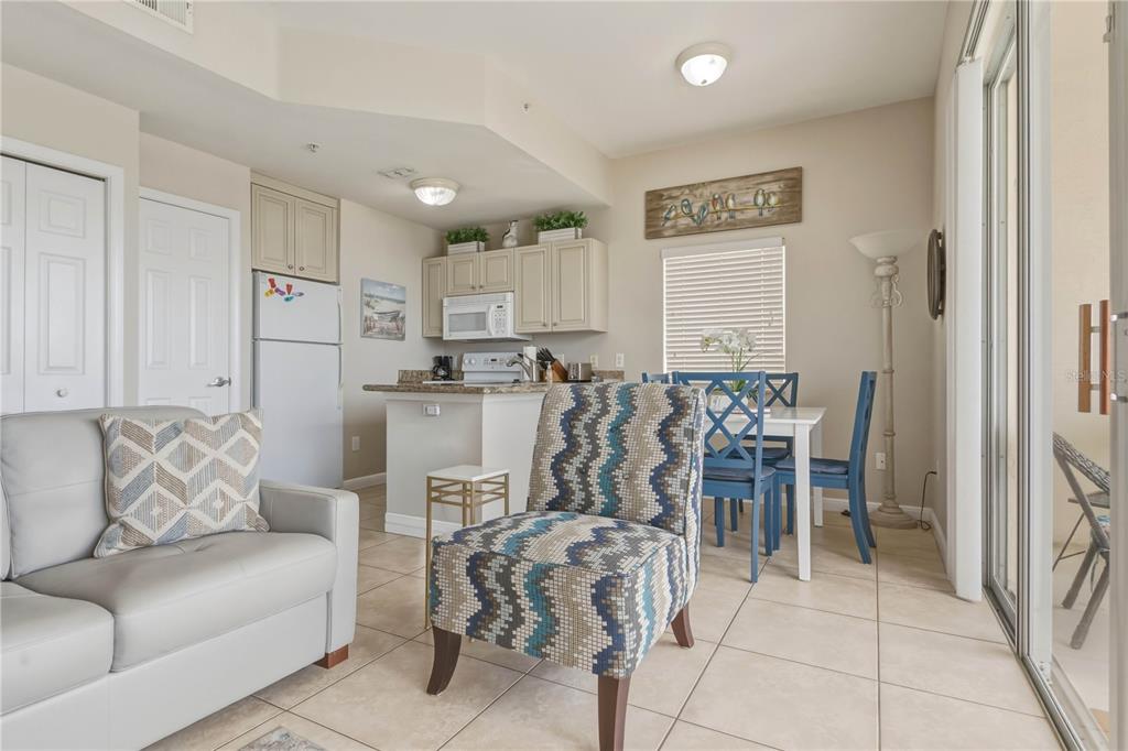 A living and dining area features tile floors, a patterned accent chair, and a kitchen — 8800 BAY PINES BOULEVARD UNIT 212, ST PETERSBURG, FL