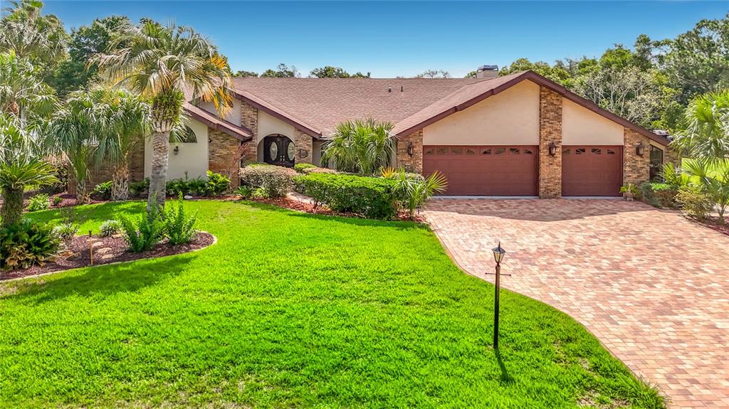 A single-story house with a brick driveway, two-car garage, and palm trees in the yard — 4306 RIVER BIRCH DRIVE, SPRING HILL, FL