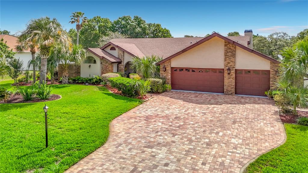 A single-story house with a brick facade, a paved driveway, and a manicured lawn — 4306 RIVER BIRCH DRIVE, SPRING HILL, FL
