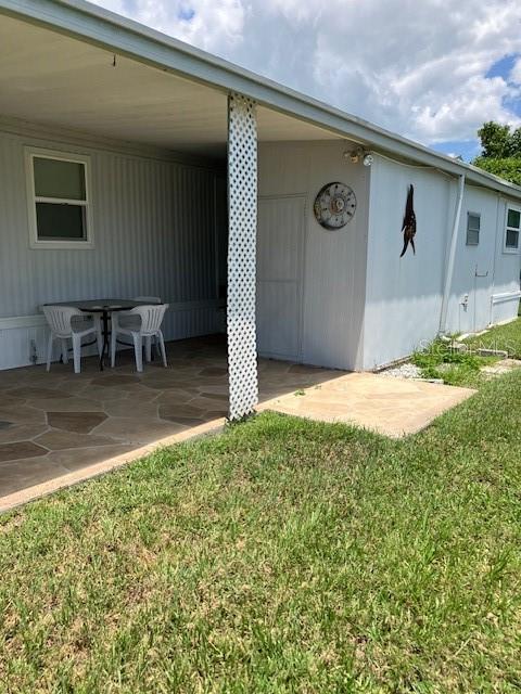 A covered patio with a stone floor and white lattice column sits beside a house — 3350 COURTNEY DRIVE, HOLIDAY, FL