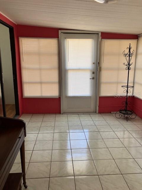 A sunroom with white tiled floors, red walls, a central door, and a metal coat rack — 3350 COURTNEY DRIVE, HOLIDAY, FL