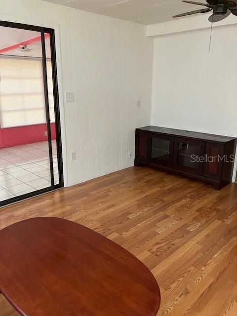 A room with wood flooring, a dark media console, and a sliding glass door — 3350 COURTNEY DRIVE, HOLIDAY, FL