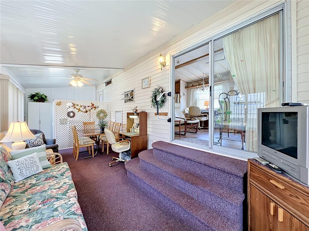 A sunroom features purple carpeting, a floral sofa, a dining set, and sliding glass doors — 9000 US HIGHWAY 192 UNIT 766, CLERMONT, FL