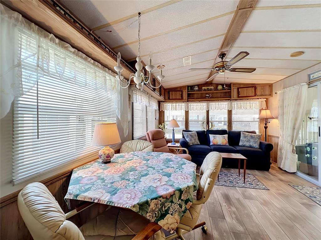 A living and dining area features wood-paneled walls, a floral tablecloth, and a blue sofa — 9000 US HIGHWAY 192 UNIT 766, CLERMONT, FL