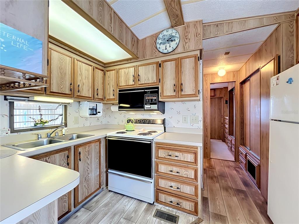 A kitchen with wood-grain cabinets, laminate countertops, a white stove, and wood-look flooring — 9000 US HIGHWAY 192 UNIT 766, CLERMONT, FL