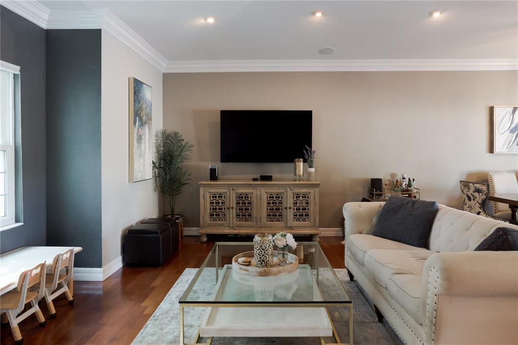 A living room features a wall-mounted television above a wooden console and a tufted sofa — 8445 SHADY GLEN DRIVE, ORLANDO, FL
