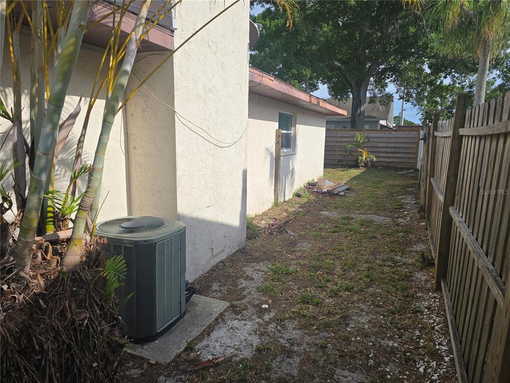 A side yard features an air conditioning unit, a stucco exterior wall, and a wooden fence — 5403 2ND AVENUE DR NW, BRADENTON, FL