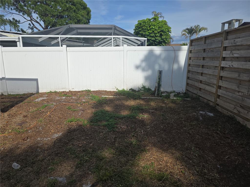 A backyard area features a white vinyl fence, a wooden fence, and sparse ground cover — 5403 2ND AVENUE DR NW, BRADENTON, FL