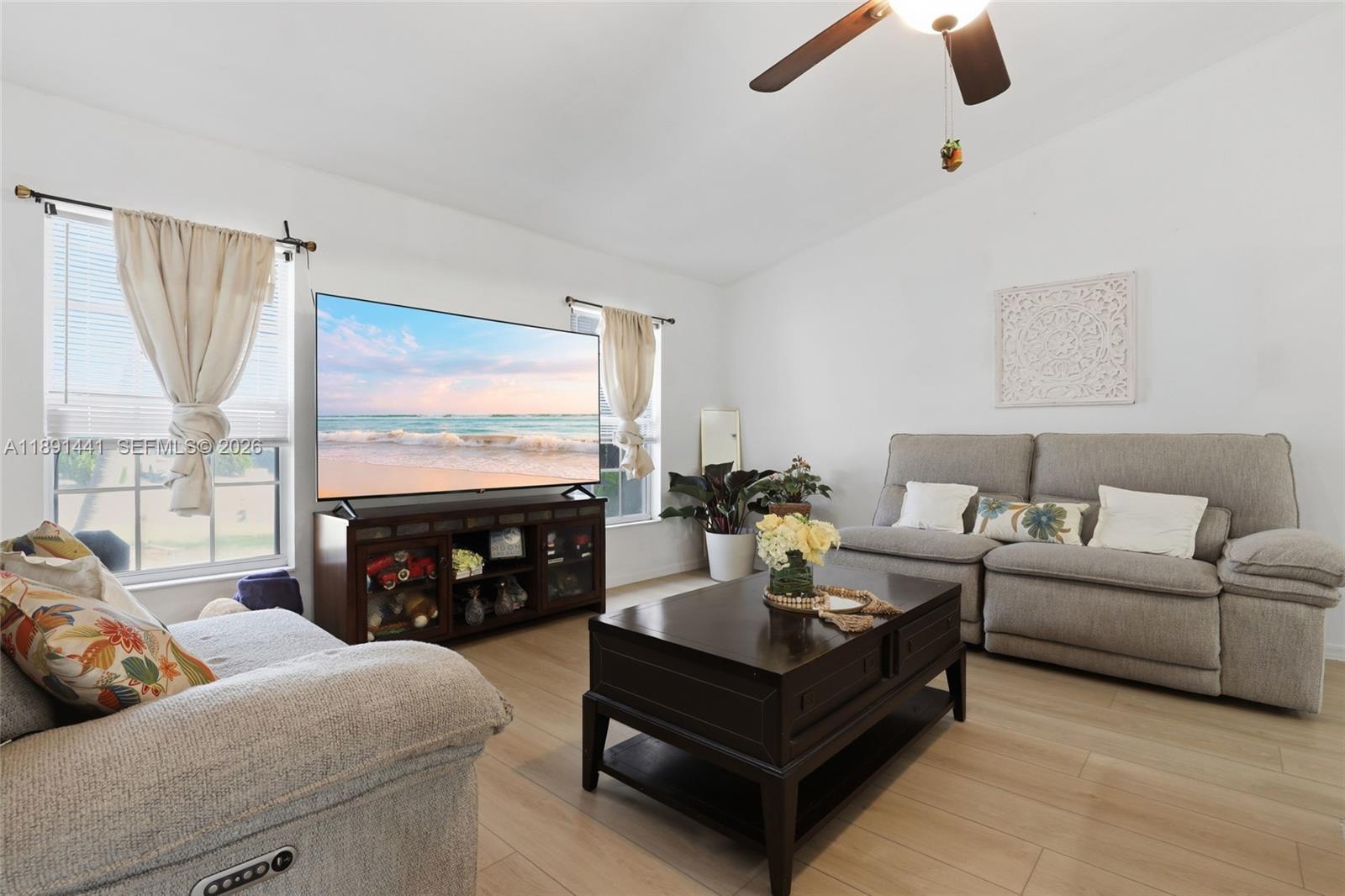 A living room features a grey sofa, a dark wood coffee table, and a television — 3003 W 25th St, Lehigh Acres FL 33971, LEHIGH ACRES, FL