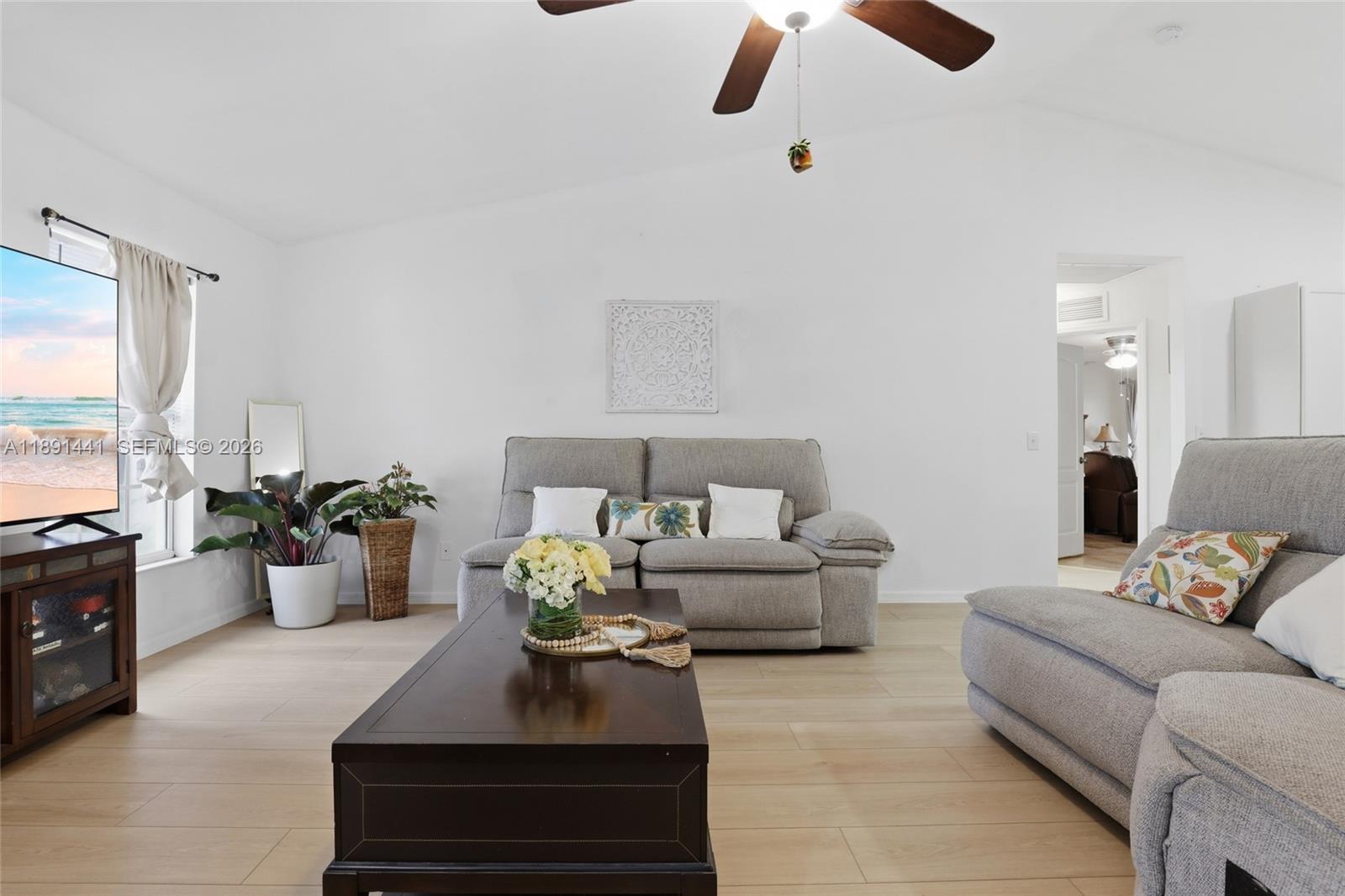 A living room features light wood flooring, a gray sofa, and a dark wood coffee table — 3003 W 25th St, Lehigh Acres FL 33971, LEHIGH ACRES, FL