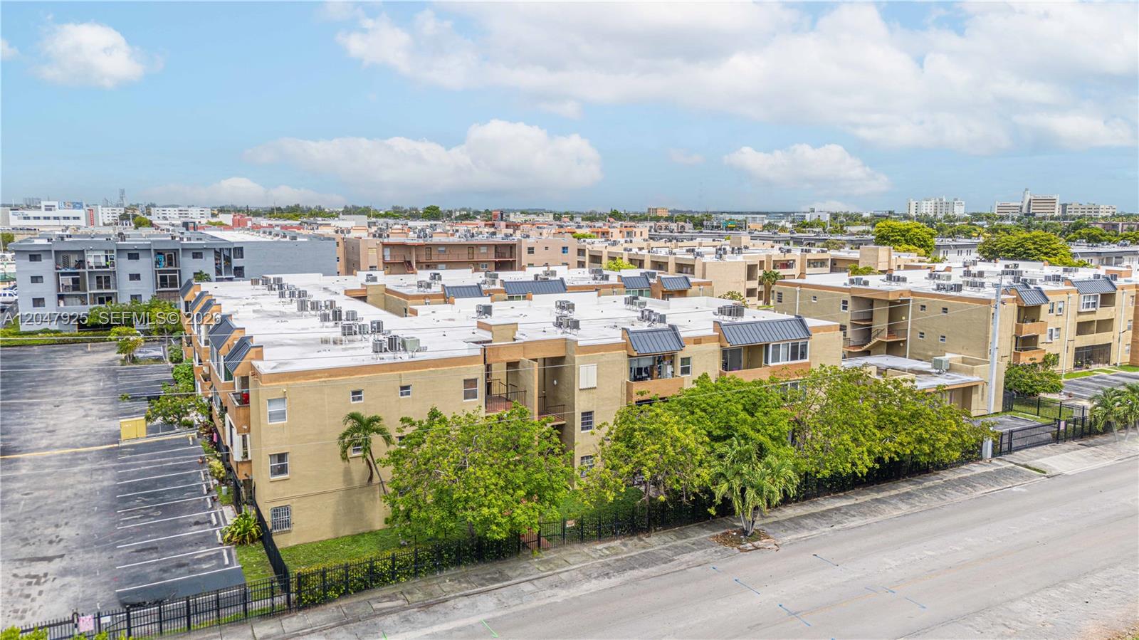 An aerial view shows a multi-story apartment complex with a parking lot and surrounding trees — 6070 W 18th Ave # 209, Hialeah FL 33012, HIALEAH, FL