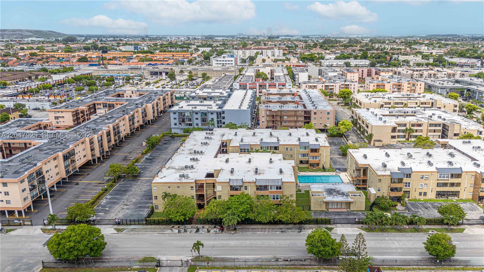 An aerial view shows multiple apartment buildings with flat roofs, parking lots, and a swimming pool — 6070 W 18th Ave # 209, Hialeah FL 33012, HIALEAH, FL