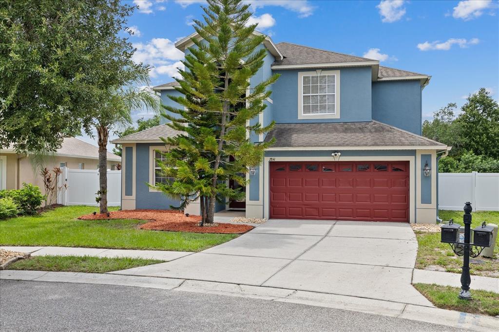 A two-story blue house with a red garage door and a large pine tree — 2841 TRINITY COTTAGE DRIVE, LAND O LAKES, FL