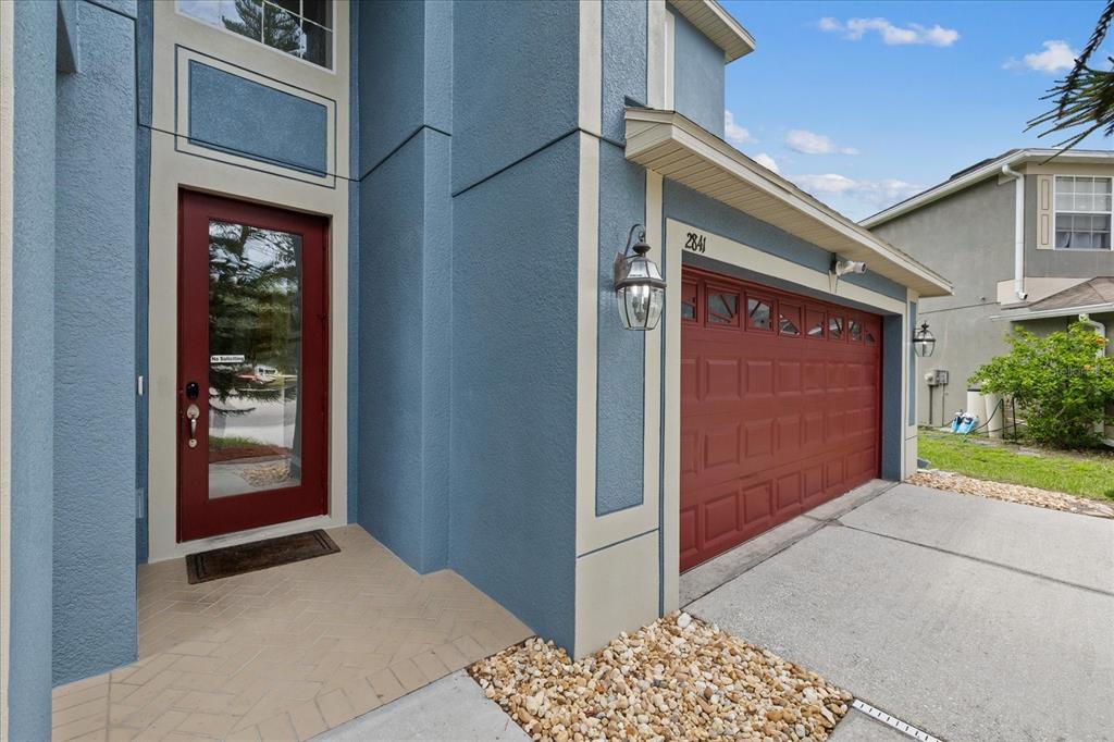 The exterior of a blue house features a red front door and a red garage door — 2841 TRINITY COTTAGE DRIVE, LAND O LAKES, FL
