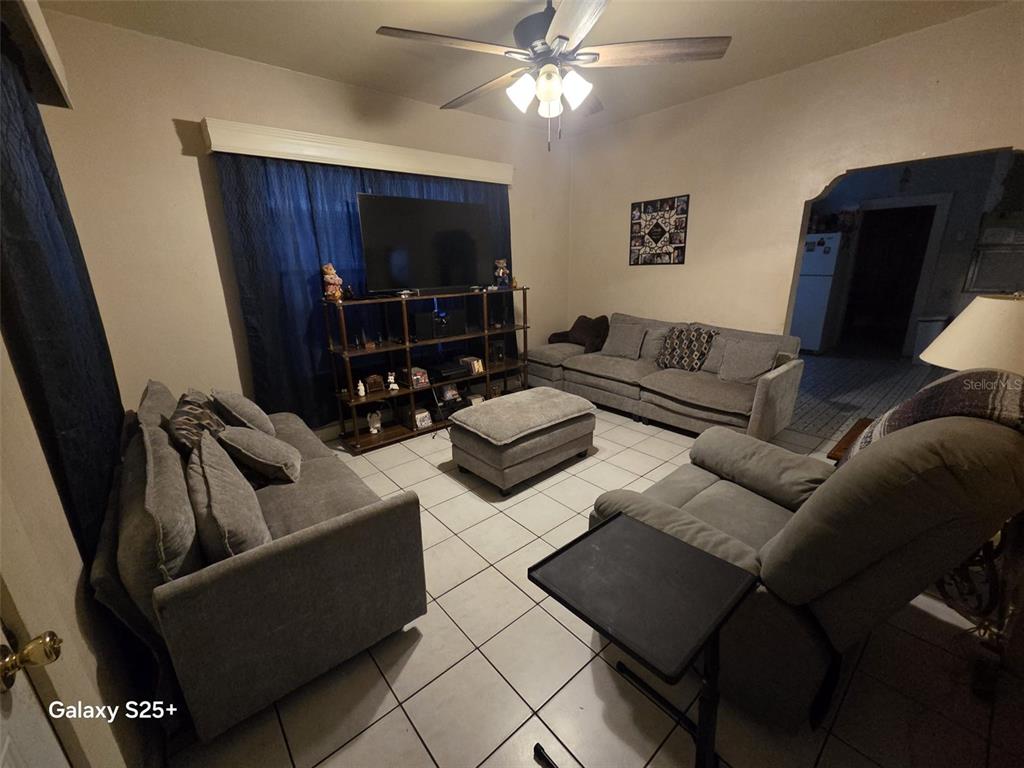 A living room features gray furniture, a large television on a shelf, and tile flooring — 1301 E 26TH AVENUE, TAMPA, FL