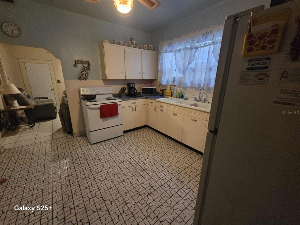 A living room features gray sofas, a central ottoman, tile flooring, and a ceiling fan — 1301 E 26TH AVENUE, TAMPA, FL