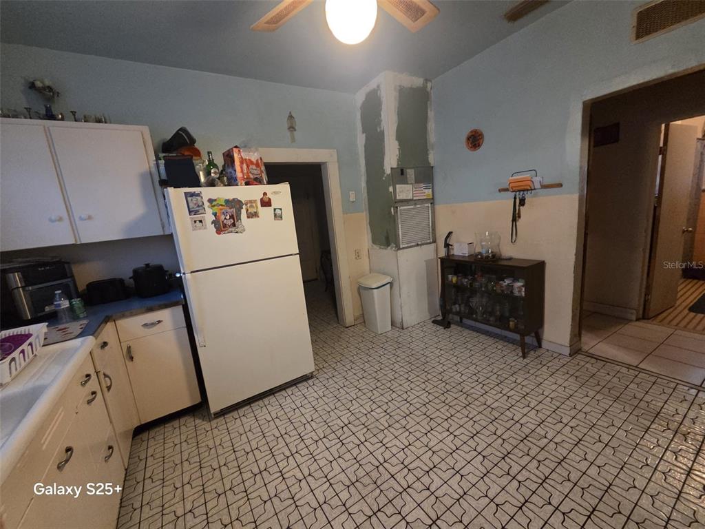 A kitchen features white cabinets, a white stove, a tiled floor, and a window — 1301 E 26TH AVENUE, TAMPA, FL