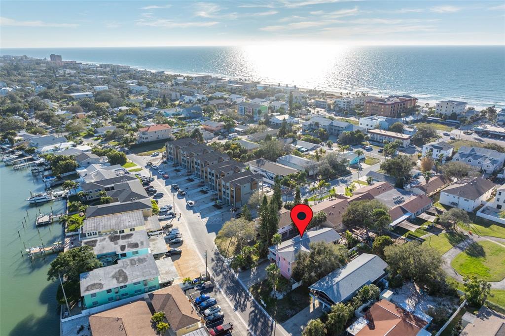 An aerial view shows a coastal neighborhood with a red pin marking a pink house — 2302 BAY BOULEVARD, INDIAN ROCKS BEACH, FL
