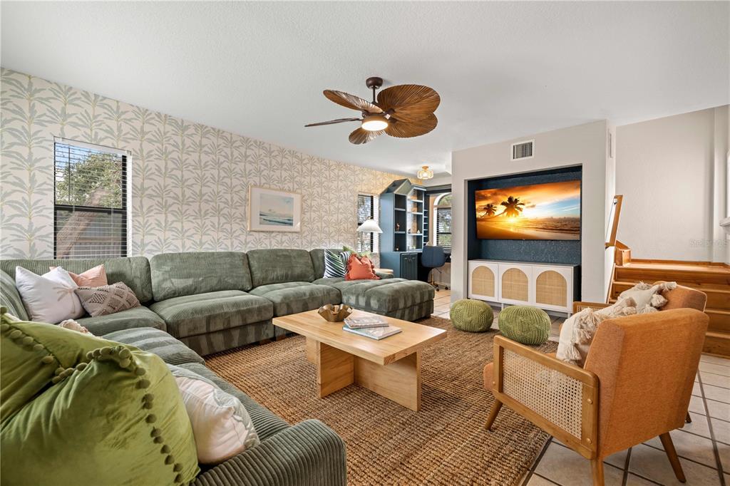 A living room features a large green sectional, a wooden coffee table, and patterned wallpaper — 2302 BAY BOULEVARD, INDIAN ROCKS BEACH, FL