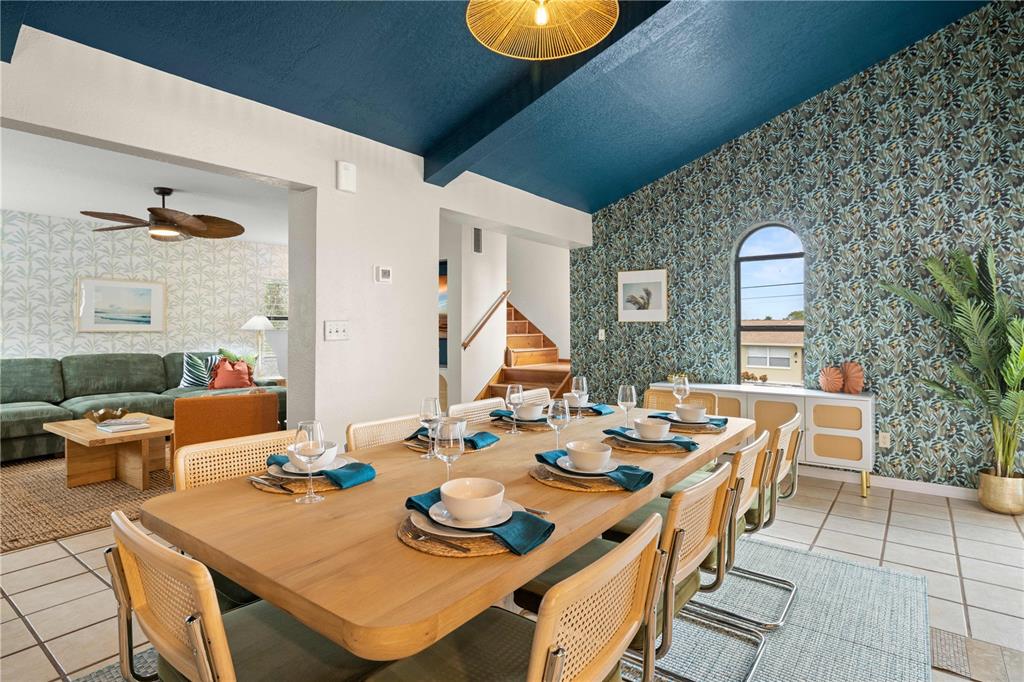 A dining room features a long wooden table, cane chairs, and a bold patterned accent wall — 2302 BAY BOULEVARD, INDIAN ROCKS BEACH, FL
