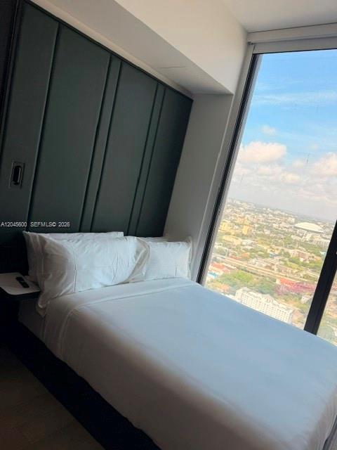 A bedroom with a dark paneled headboard and a large window overlooking a city skyline — 20 NE 11th ST # 4807A, Miami FL 33132, MIAMI, FL