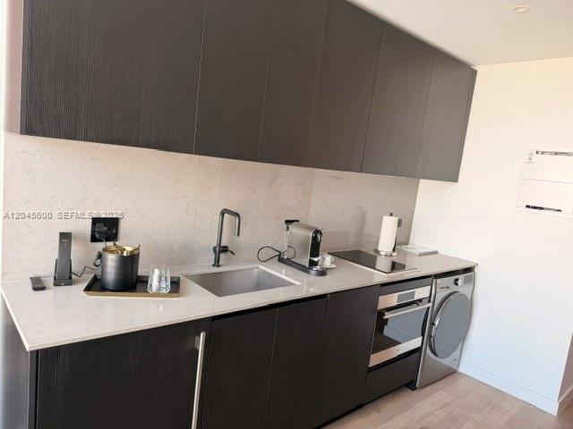 A modern kitchen features dark wood cabinetry, white countertops, a sink, and a built-in washer — 20 NE 11th ST # 4807A, Miami FL 33132, MIAMI, FL
