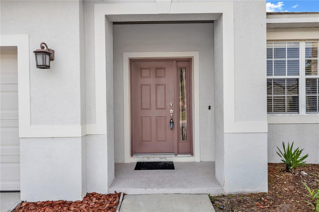 A front entrance features a mauve door with a sidelight and a black doormat — 14249 QUEENSIDE STREET, ORLANDO, FL
