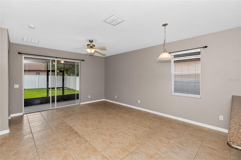 An empty dining area features tan tile flooring, a ceiling fan, and sliding glass patio doors — 14249 QUEENSIDE STREET, ORLANDO, FL