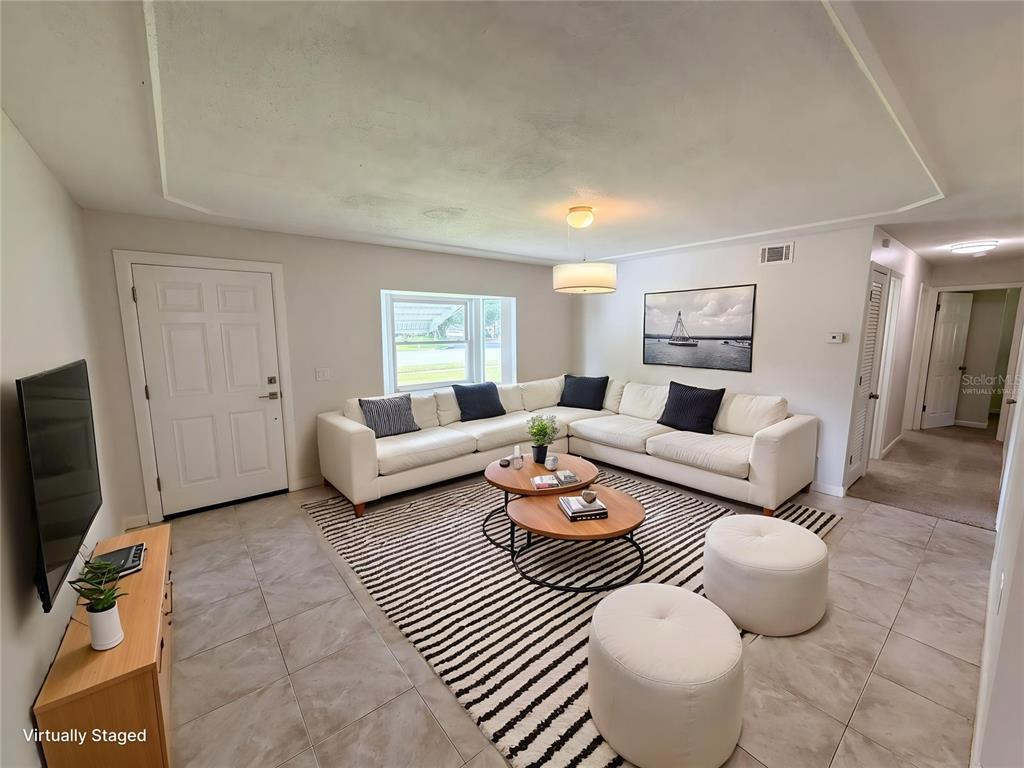 A living room features a white sectional sofa, two round coffee tables, and striped rug — 1057 LAKEMOOR BOULEVARD, ROCKLEDGE, FL