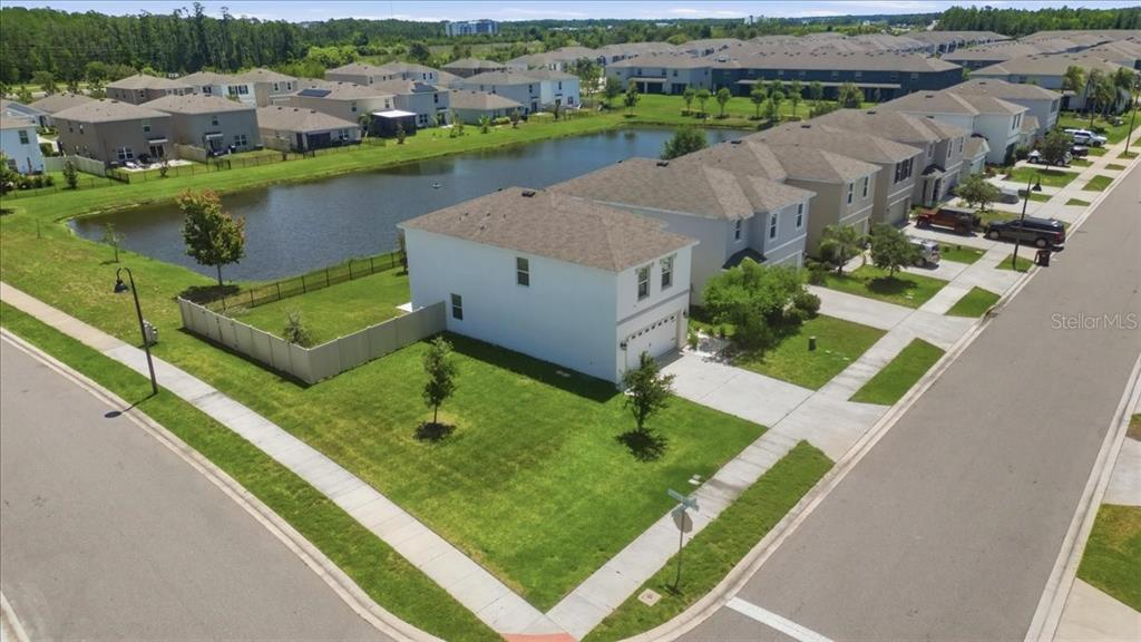 An aerial view shows a white two-story house with a fenced yard beside a pond — 3126 SUNCOAST BLEND DRIVE, ODESSA, FL