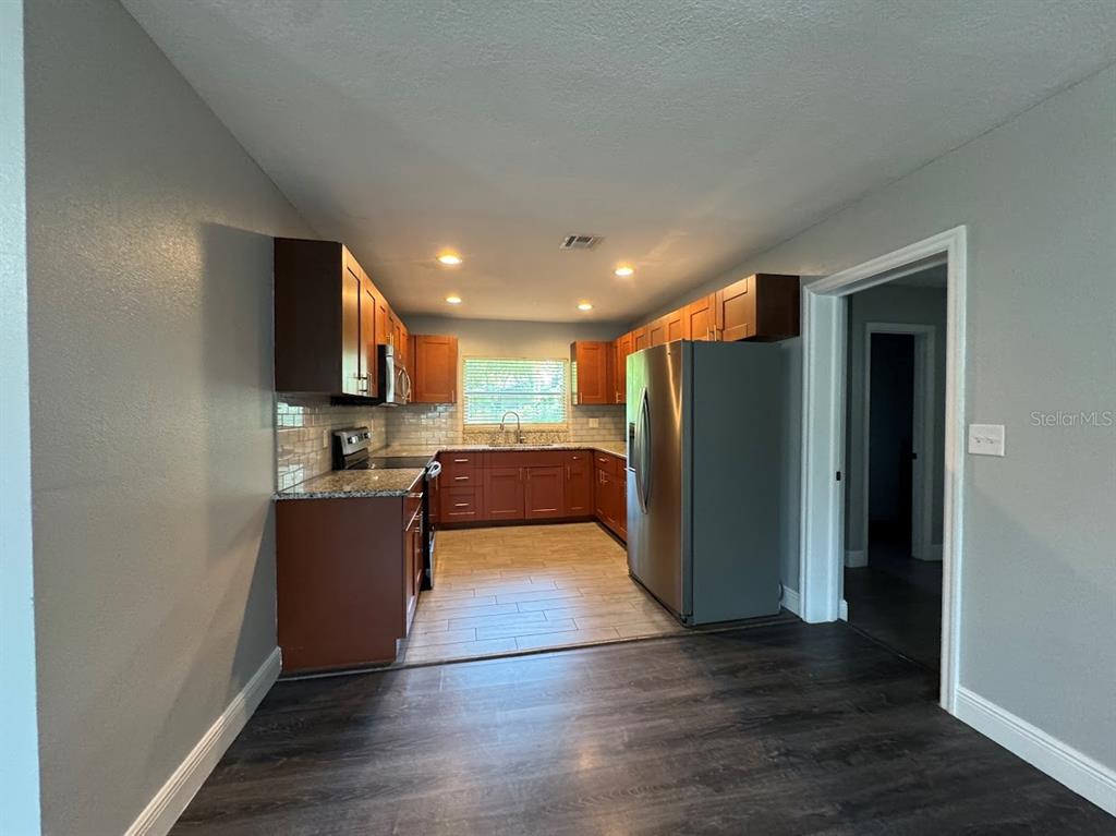 A kitchen features wood cabinets, granite countertops, stainless steel appliances, and tile flooring — 2125 CARLTON DRIVE, ORLANDO, FL