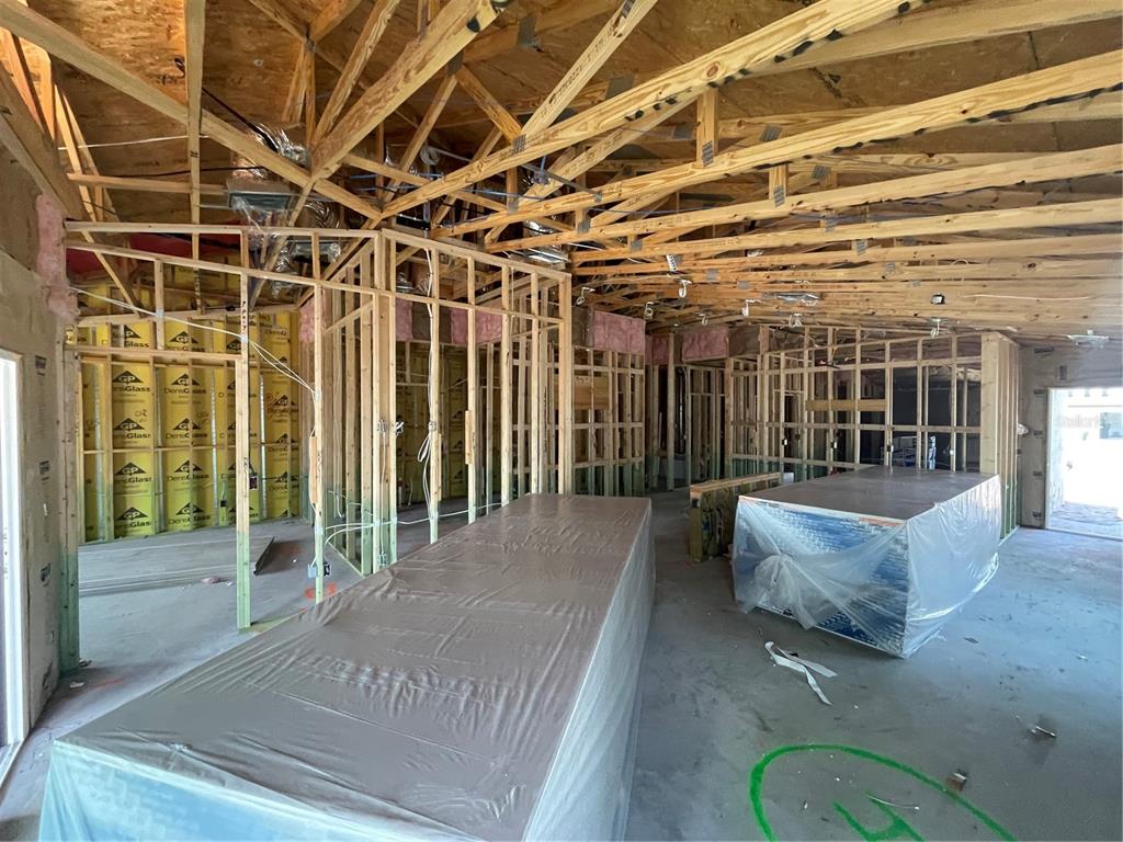 An interior view of a house under construction with exposed wooden framing and drywall stacks — 12365 OAK  HILL WAY, PARRISH, FL