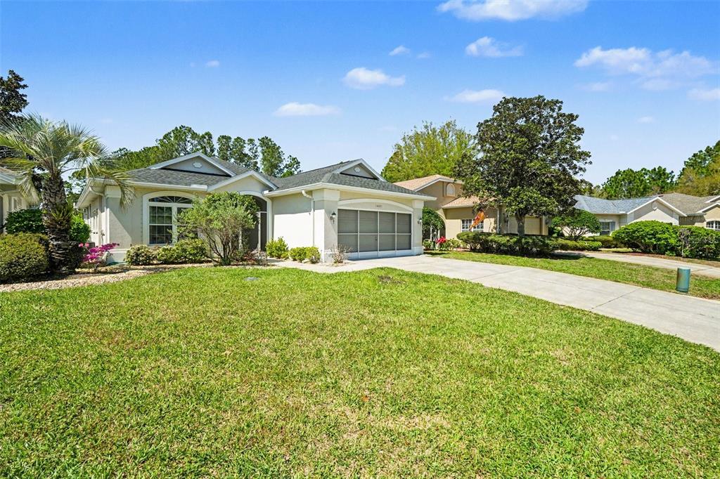 A single-story house with a beige exterior, a two-car garage, and a green lawn — 10093 HOLLY BERRY DRIVE, WEEKI WACHEE, FL