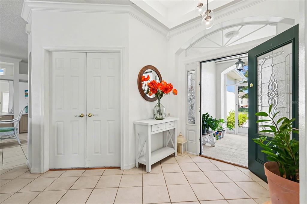 A bright entryway features white walls, tile flooring, a console table, and an open front door — 10093 HOLLY BERRY DRIVE, WEEKI WACHEE, FL