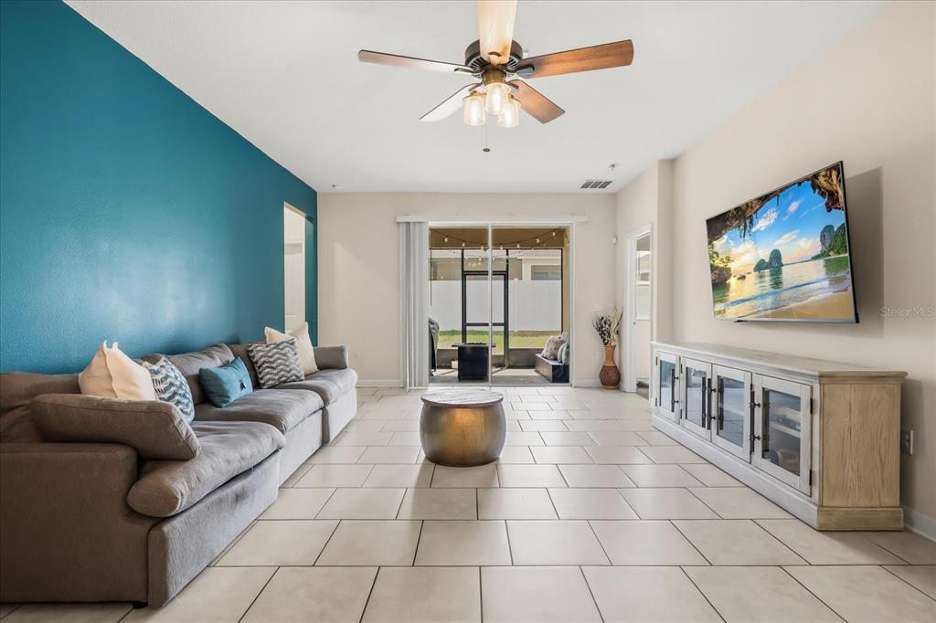 A living room features a grey sofa, a media console, and a sliding glass door — 133 TAFT DRIVE, DAVENPORT, FL