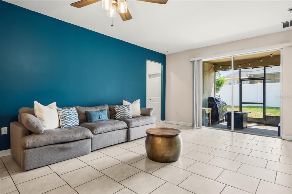 A living room features a blue accent wall, gray sectional sofa, and sliding glass doors — 133 TAFT DRIVE, DAVENPORT, FL